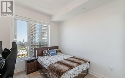 A bedroom with a large bed and a view of a cityscape through the window.