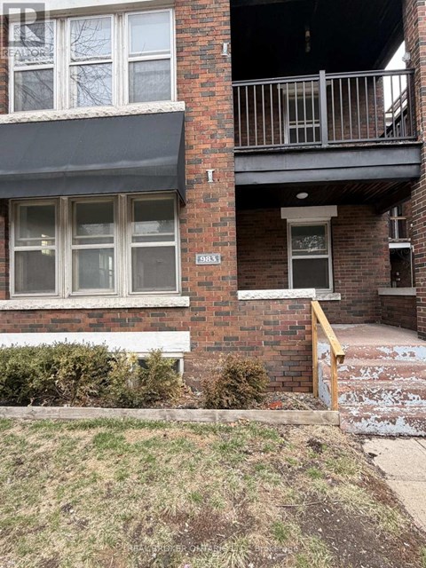 A brick building with a balcony and a small garden in front.
