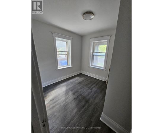 A room with two windows and a wooden floor.