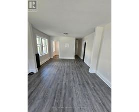 A spacious room with wood flooring and white walls.