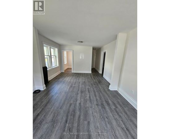 A spacious room with wood flooring and white walls.