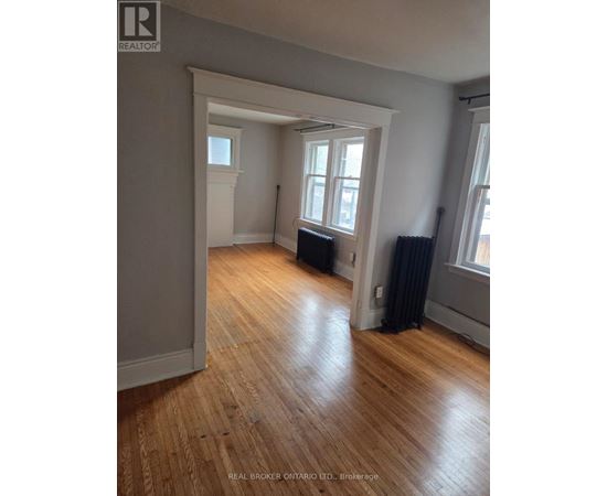 A room with wooden floors and a window with black curtains.