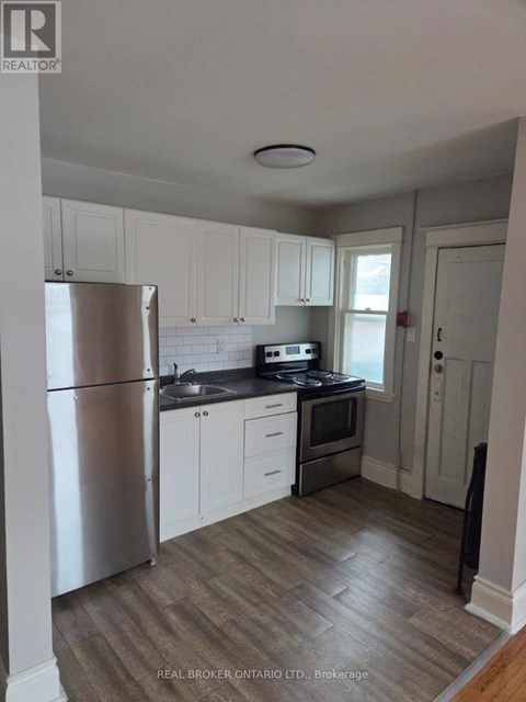 A kitchen with white cabinets and a stainless steel refrigerator.