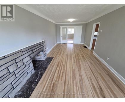 A long hallway with wooden floors and a brick wall on the side.