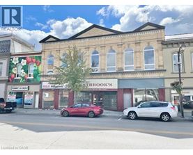 A street view with a red car parked in front of a building with a sign that says "ESTBROOK'S".