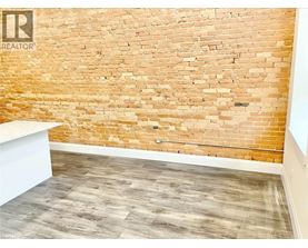 A room with a brick wall and wooden floor.