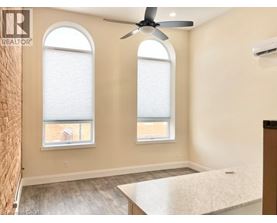 A room with a ceiling fan and two windows.