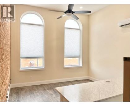 A room with a ceiling fan and two windows.