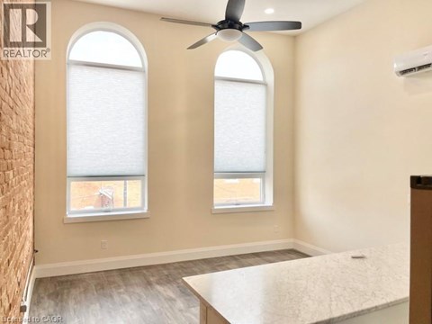 A room with a ceiling fan and two windows.