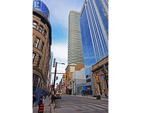 A city street with a mix of old and new buildings, with a blue sky above.