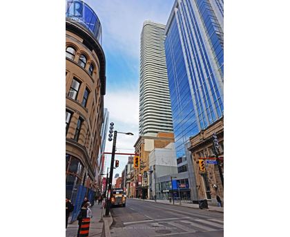 A city street with a mix of old and new buildings, with a blue sky above.