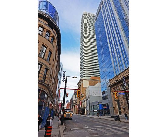 A city street with a mix of old and new buildings, with a blue sky above.