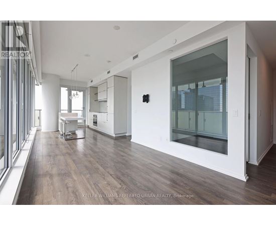 A modern kitchen with white cabinets and a wooden floor.