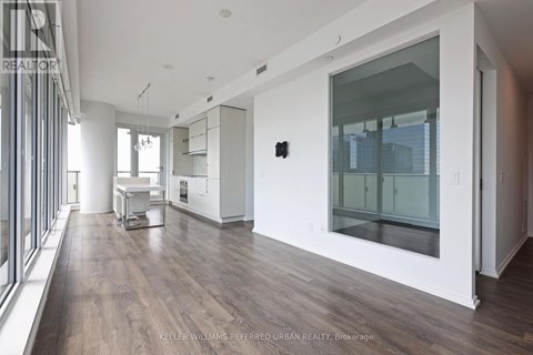 A modern kitchen with white cabinets and a wooden floor.