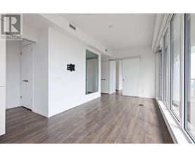 A spacious room with wood flooring and white walls.