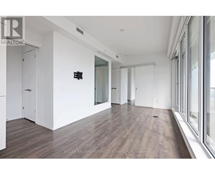 A spacious room with wood flooring and white walls.