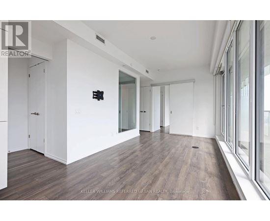 A spacious room with wood flooring and white walls.