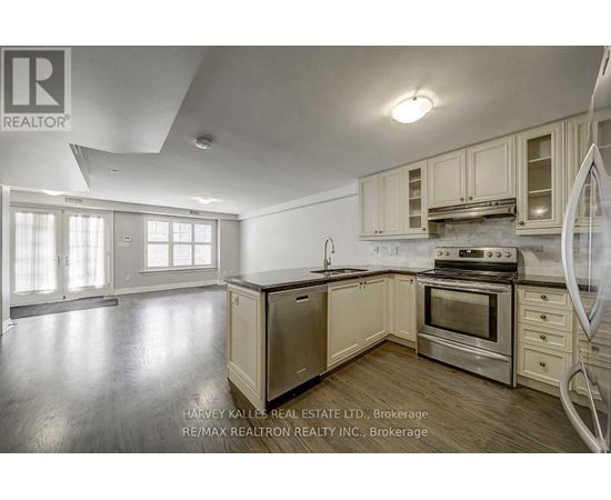 A kitchen with a refrigerator, oven, and cabinets.