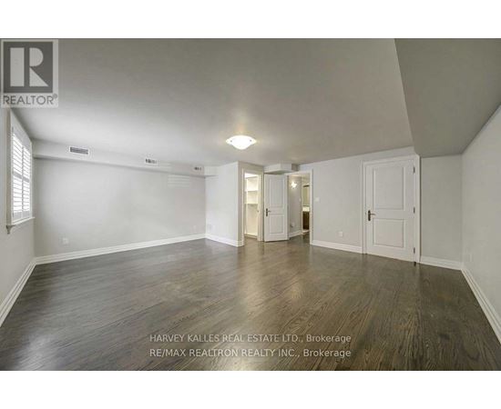 A spacious room with wooden flooring and white walls.