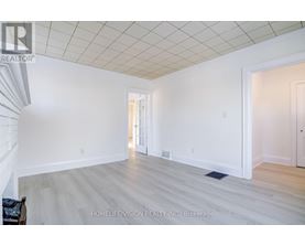 A spacious room with a white ceiling and light wood flooring.