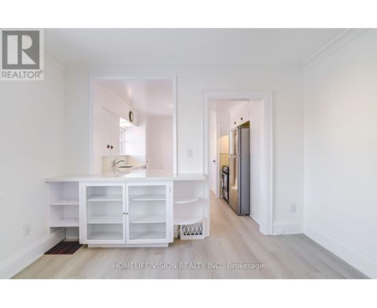 A white kitchen with a refrigerator and cabinets.