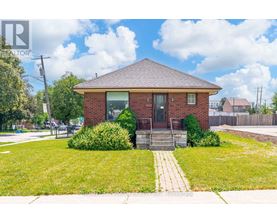 A small red brick house with a front yard and a walkway leading to the front door.
