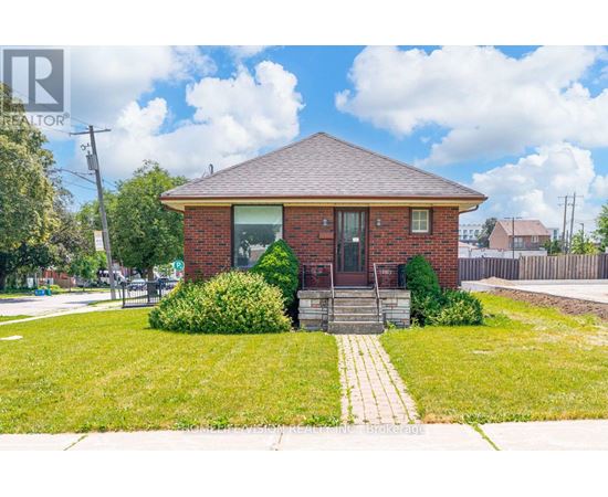 A small red brick house with a front yard and a walkway leading to the front door.