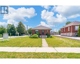 A realtor sign is in front of a grassy area with a house in the background.