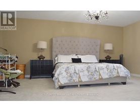 A bedroom with a large bed and a chandelier.