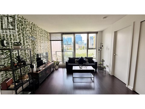 A living room with a black couch and a patterned wallpaper.