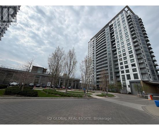 A modern apartment building with a parking lot in front.