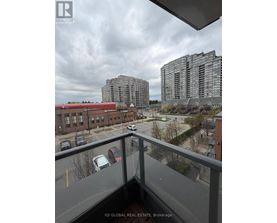 A view from a balcony overlooking a parking lot and buildings.