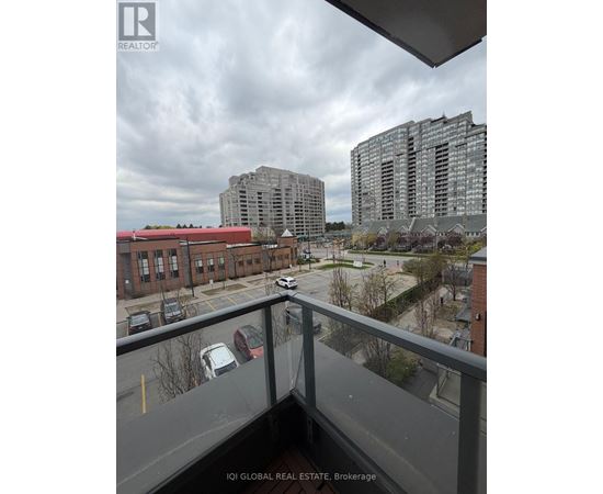 A view from a balcony overlooking a parking lot and buildings.