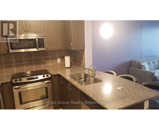 A modern kitchen with a stove top oven, microwave, and a granite counter top.
