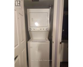 A white dryer is in a small space next to a door.