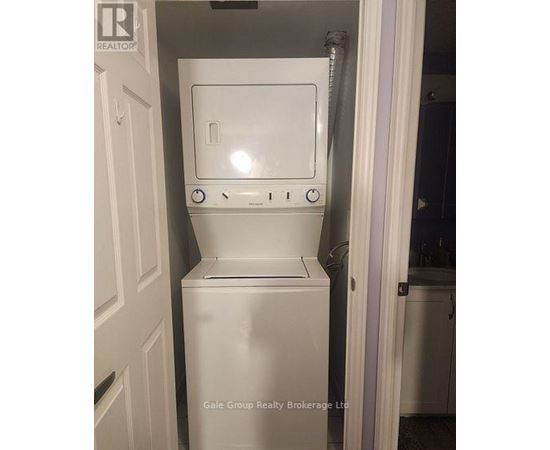 A white dryer is in a small space next to a door.