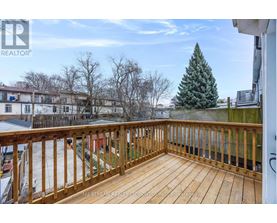 A wooden deck with a railing and a tree in the background.
