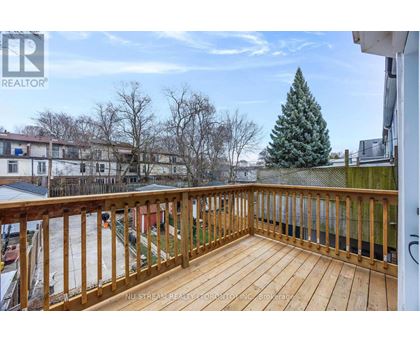 A wooden deck with a railing and a tree in the background.