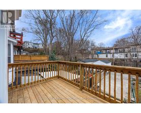 A wooden deck with a railing and a view of a residential area.