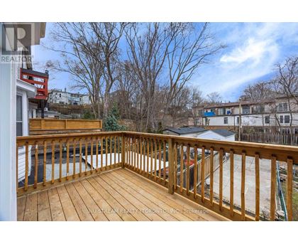 A wooden deck with a railing and a view of a residential area.