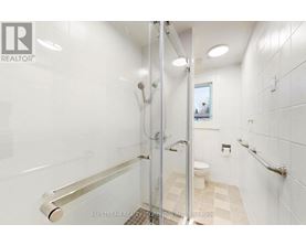 A white bathroom with a walk-in shower and a toilet.