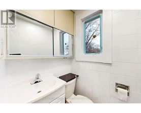 A white bathroom with a toilet, sink, and mirror.