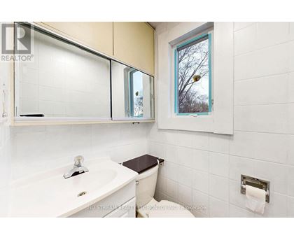 A white bathroom with a toilet, sink, and mirror.