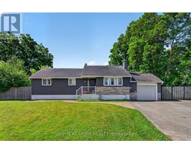 A house with a grey roof and a white garage door is for sale.