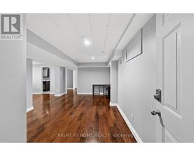 A spacious room with wooden floors and white walls, with a door on the right side.