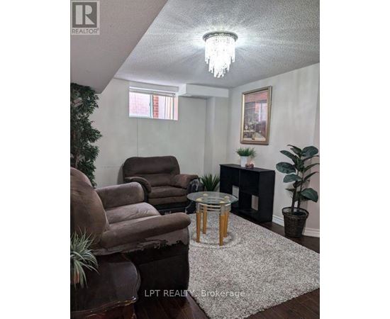 A living room with a brown chair, a glass table, and a potted plant.