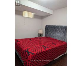 A bed with a red and black patterned comforter in a bedroom.
