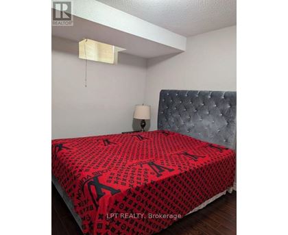 A bed with a red and black patterned comforter in a bedroom.