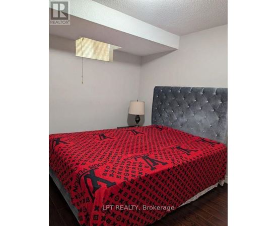 A bed with a red and black patterned comforter in a bedroom.