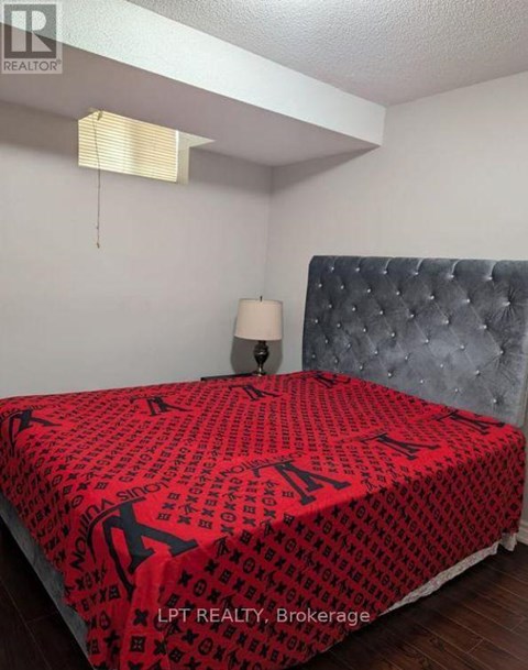 A bed with a red and black patterned comforter in a bedroom.